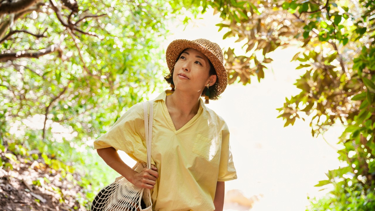 Woman in bright yellow shirt walking through a forest