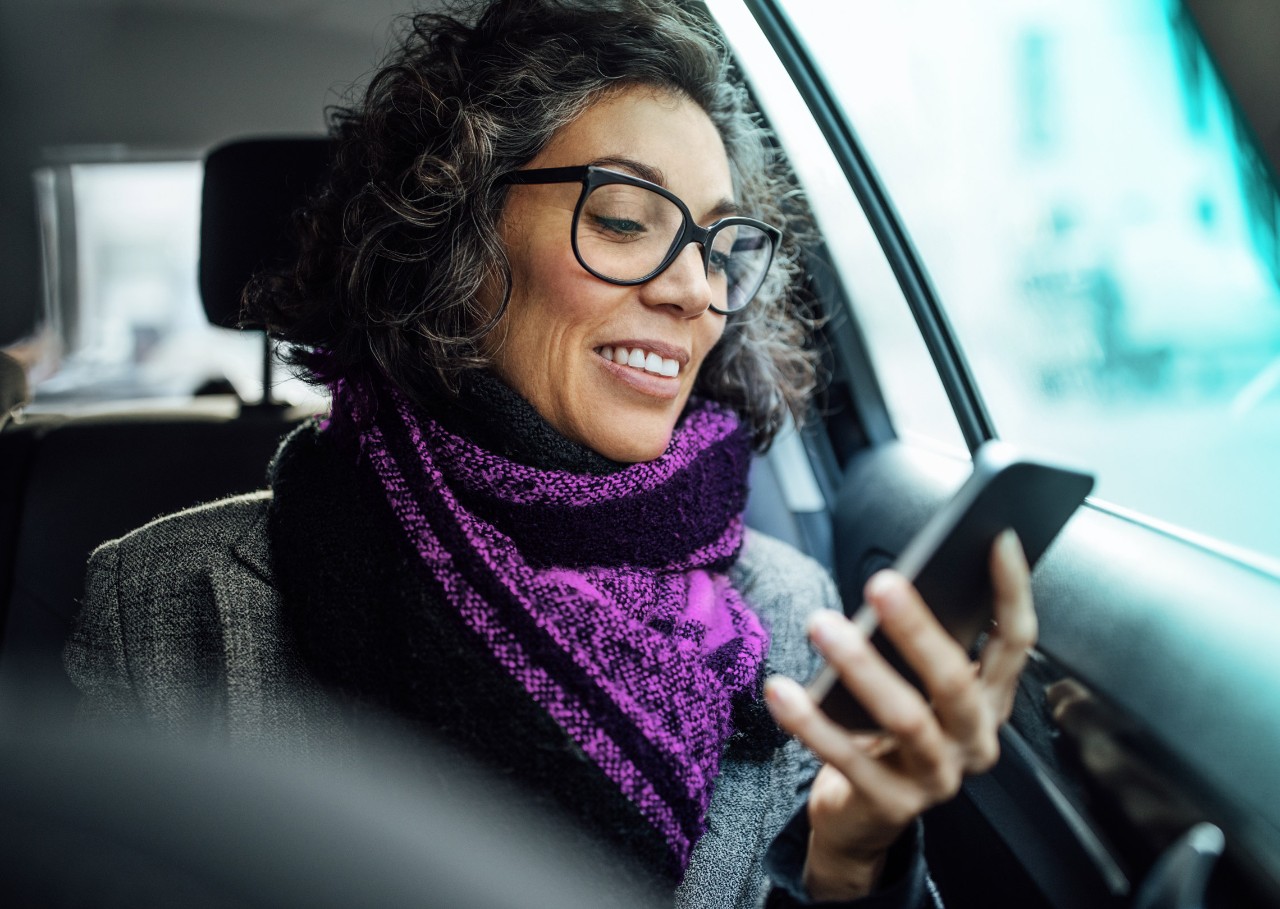 mature woman in car looking at her smartphone 