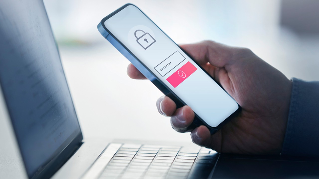 Man holding smart phone with data security on display at office