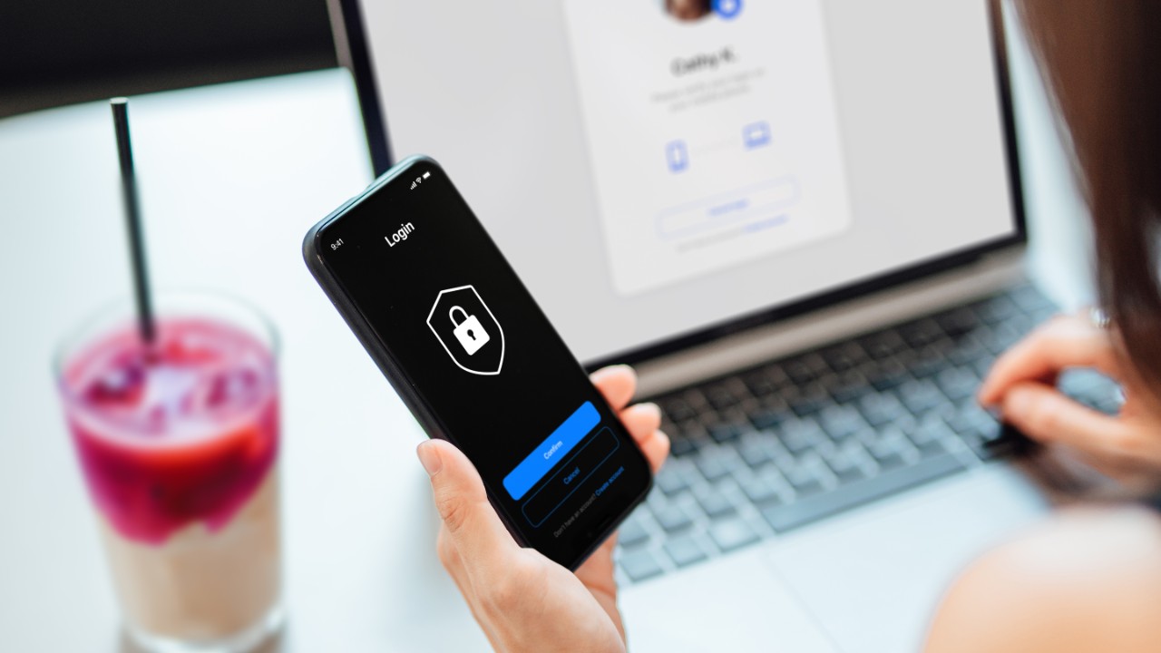 Young Business Woman Logging in Online Security System On Laptop With Mobile App On Smartphone